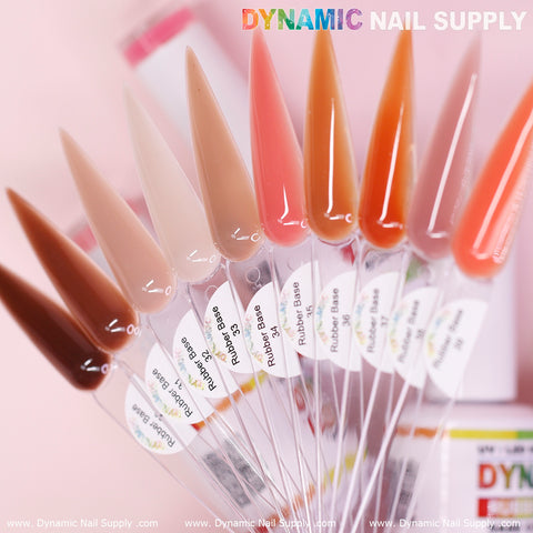 A display of nail polish swatches exhibits an array of nude shades on extended samples from the (BIAB) Rubber Base gel (Builder Gel in a Bottle) Number 30 to 39 collection. Each sample is marked with product numbers and names such as Rubber Base gel. The background displays the blurred text and colorful branding of Dynamic Nail Supply.