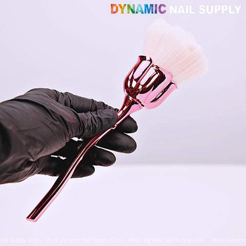 A hand in a black glove holds a [Metal Pink] Rose Nail Dust Cleaner Brush for Dip Powder on a plain background.