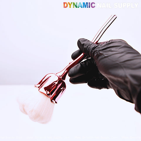 A gloved hand holds the [Metal Pink] Rose Nail Dust Cleaner Brush for Cleaning Dust Dip Powder with white bristles.