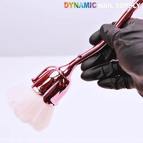 A gloved hand holds the [Metal Pink] Rose Nail Dust Cleaner Brush with white bristles; “DYNAMIC NAIL SUPPLY” is on top.