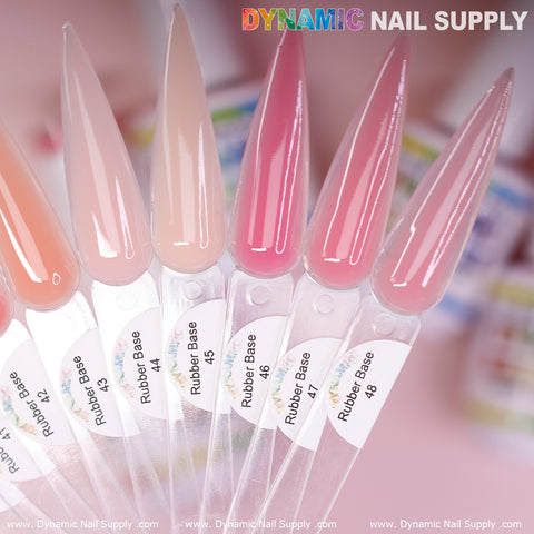 Displayed are elongated, nail-shaped samples featuring a spectrum of pink shades. Each sample is labeled with Rubber Base Gel from the Builder Gel in a Bottle (BIAB) collection, numbered 40 to 48. The background is artistically blurred, highlighting the Dynamic Nail Supply brand name at the top and their website URL elegantly positioned at the bottom edge.