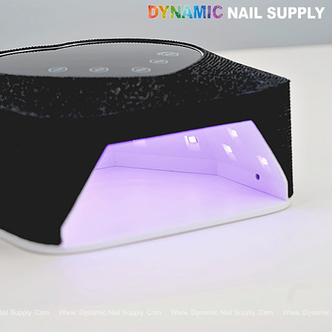 A Black Small Rhinestone UV/LED 72W Cordless Lamp glows purple, heart-shaped display, DYNAMIC NAIL SUPPLY logo above.