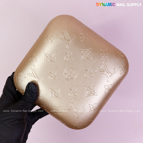 A hand holds the Metallic Gold LV Engrave Elbow Rest Pillow—soft, supportive PU leather—on a pale pink background.