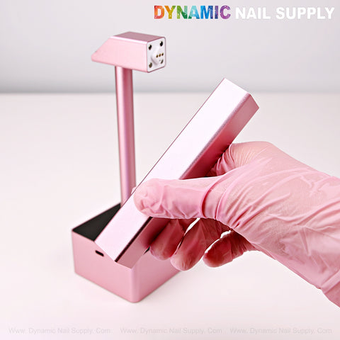 A nail tech uses a pink 2 in 1 Mini UV/LED Flash Cure Handheld Light with its Portable Stand Lamp base.