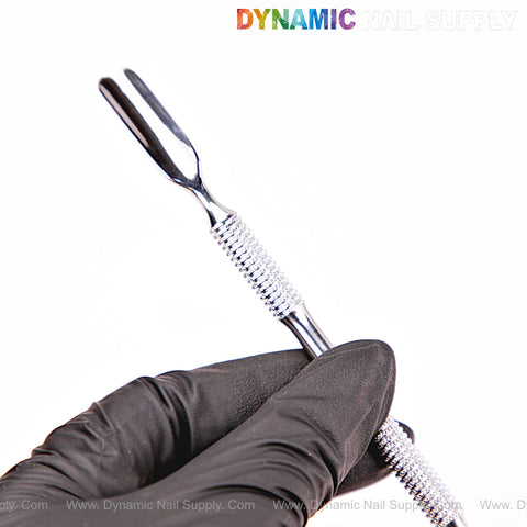A gloved hand holds the NT1234 – Professional Double-Function Cuticle Pusher before a white background.