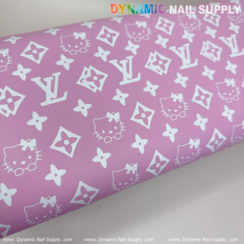 Close-up of a pink surface featuring a pattern of white icons, including cartoon cat faces and stylized floral and geometric shapes. The background is decorated with the Dynamic Nail Supply logos in multiple colors along the top edge, making it ideal for displaying with manicure nail services. This high-quality product is the (Pink Hello Kitty LV) Nails Pillow ArmRest with Leather Cushion for Manicure Pedicure from Dynamic Nail Supply.