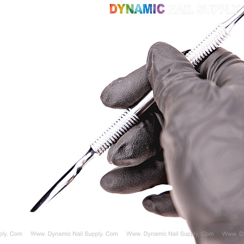 A gloved hand holds the NT1234 Professional Double-Function Cuticle Pusher against a white background.