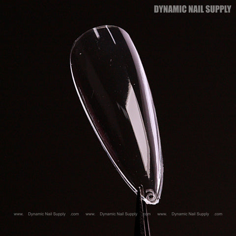 A Natural Stiletto (Medium) Full Cover Soft-Gel Nail Tip is held upright by tweezers against a black background.