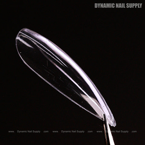 A Natural Stiletto (Medium) Full Cover Soft-Gel Nail Tip is held by tweezers with DYNAMIC NAIL SUPPLY text visible.