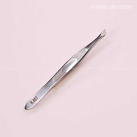 N407 Professional Slanted Tweezers in stainless steel with textured grip, shown on a pale pink background.