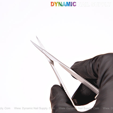 A gloved hand holds NT1243 Professional Stainless Steel Cuticle Spring Scissors with DYNAMIC NAIL SUPPLY text above.
