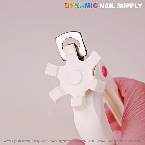 A gloved hand holds the Nail Tip Cutter With Measure Spacers, an adjustable manicure tool, against a light background.
