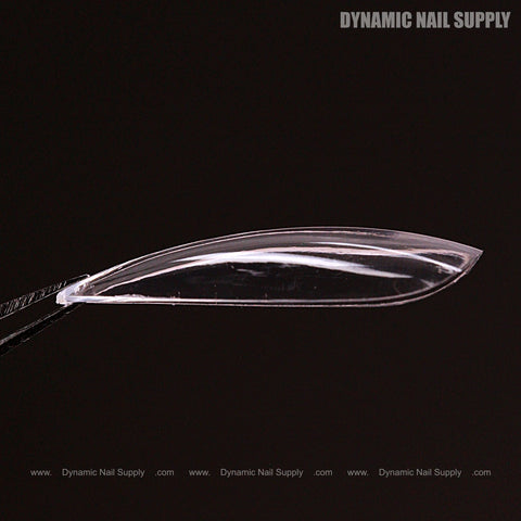 A Natural Stiletto (Medium) Full Cover Soft-Gel Nail Tip (Pink Box) is held by tweezers against a black background.