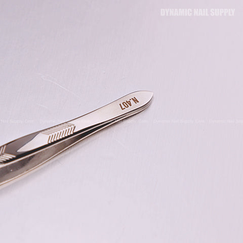 Close-up of the N407 Professional Slanted Head Tweezers, stainless steel, on a light reflective surface.