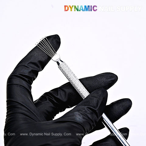 Hand in black glove holds Nail Art Manicure Stainless Steel Brush Clamping Tool; DYNAMIC NAIL SUPPLY logo above.