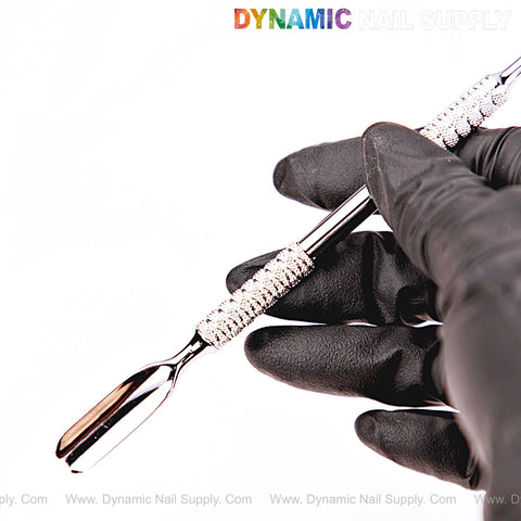 A gloved hand holds the NT1230 Professional Double-Function Cuticle Pusher; DYNAMIC NAIL SUPPLY text above.