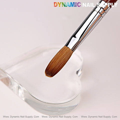 A Size 16 Dynamic Kolinsky Brush hovers above a clear heart-shaped dish on a white background.