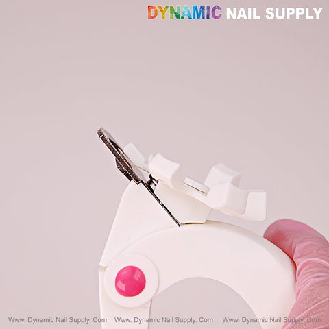 A gloved hand holds the Nail Tip Cutter With Measure Spacers, an adjustable manicure tool, against a light background.