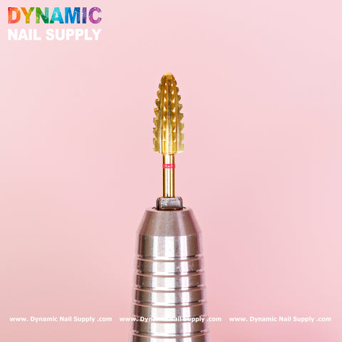 A close-up showcases the 2XC Typhoon Bit, a gold nail drill bit with a textured, tapered design, perfect for removing acrylic or gel polish. It stands on a metallic holder against a pink background. The top left displays vibrant text reading "Dynamic Nail Supply," while the website www.DynamicNailSupply.com is repeated along the bottom border.