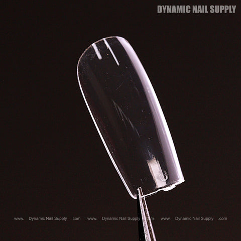 A clear Sculpted Square (Medium) Full Cover Soft-Gel Nail Tip held by tweezers, with Dynamic Nail Supply shown above.