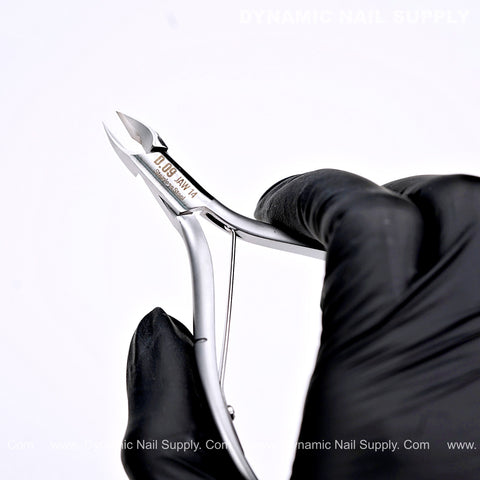 A gloved hand holds D09 - Jaw 14 Cuticle Clippers with Grip Control, designed for clean and precise cuticle removal.
