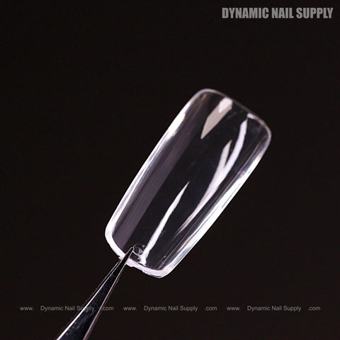 A clear Sculpted Square (Medium) Full Cover Soft-Gel Nail Tip held by tweezers; “DYNAMIC NAIL SUPPLY” in corner.