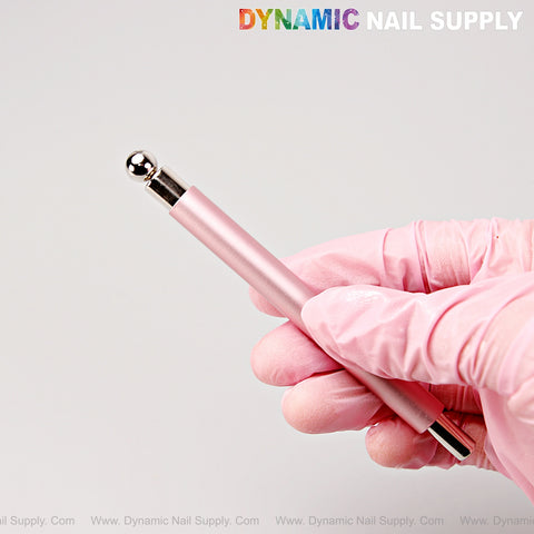 A gloved hand holds the Metallic Pink Dual Head Strong Cat Eye Magnet Nail Art Tool, featuring a silver ball tip.