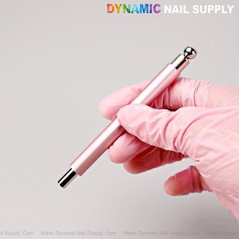 Gloved hand holds [Metallic Pink] Dual Head Strong Cat Eye Magnet Gel Nail Art Tool; DYNAMIC NAIL SUPPLY top right.