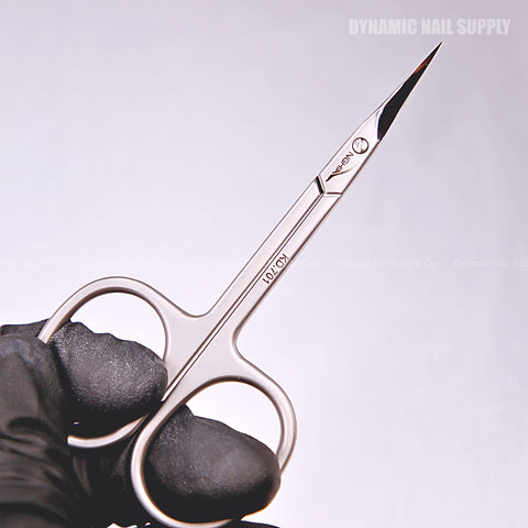 A gloved hand holds KD.701 Professional Cuticle Scissors with curved, pointed stainless steel tips against a plain background.