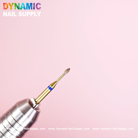 The image features a Medium Fine Cuticle Drill Bit with a Tiny Ellipse Head, ideal for Russian nail manicures and precise cuticle area cleaning. The drill bit has a smooth cylindrical handle and is set against a soft pink background, highlighting the vibrant Dynamic Nail Supply logo and website URL at the top.