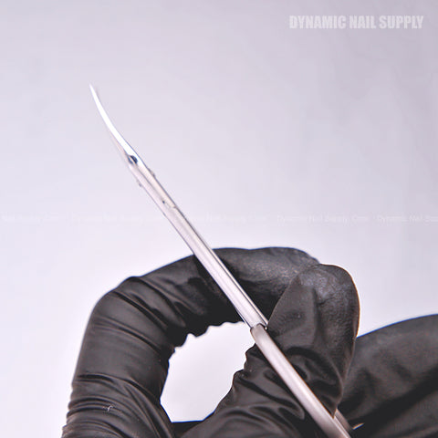A gloved hand holds KD.701 Professional Cuticle Scissors with curved stainless steel tips against a white background.