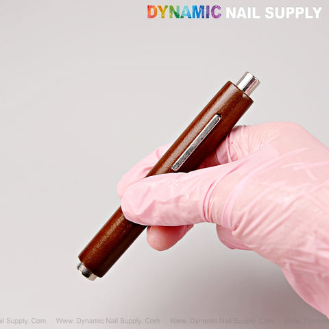 A hand in a pink glove holds the Multi-Functional Dual Head Wooden Handle Cat Eye Nail Magnet Pen; logo above.