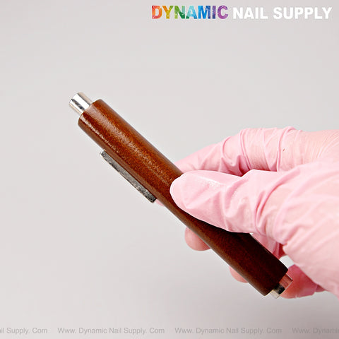 A gloved hand holds the Multi-Functional Dual Head Wooden Handle Cat Eye Nail Magnet Pen against a plain background.