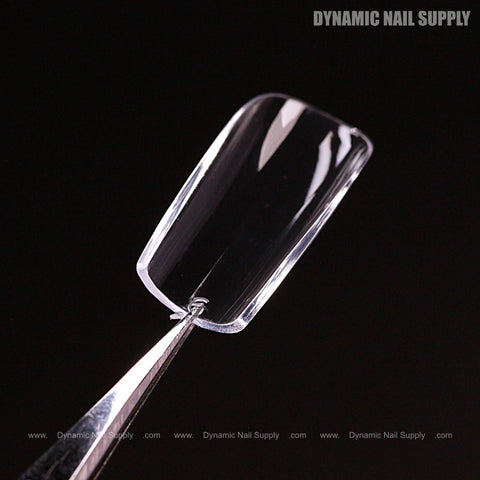 A Natural Square (Short) Full Cover Soft-Gel Nail Tip is held by tweezers; Dynamic Nail Supply watermark in view.