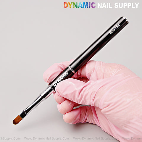 A hand in a pink glove holds the Black Builder Poly Hard Gel Dual Head Nail Art Brush with oval brush and spatula.