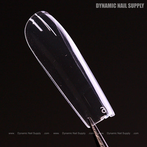 A Natural Square (Long) Soft-Gel Nail Tip (Pink Box) is held by tweezers against a solid black background.