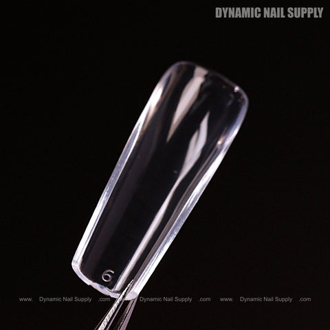 A clear, glossy Natural Square (Long) Soft-Gel Nail Tip held by tweezers with pink box and logo in corner.