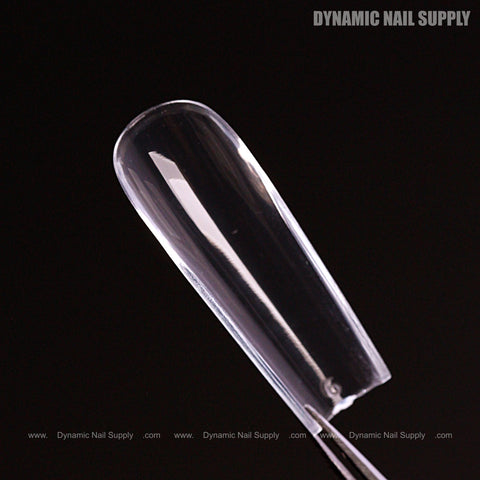 A clear, elongated Natural Square (Long) Full Cover Soft-Gel Nail Tip (Pink Box) on black with Dynamic Nail Supply text.