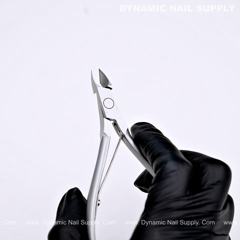 A gloved hand holds the D06 Jaw 16 Professional Nail Nippers, a sharp cuticle cutter for salon or home use, on white.