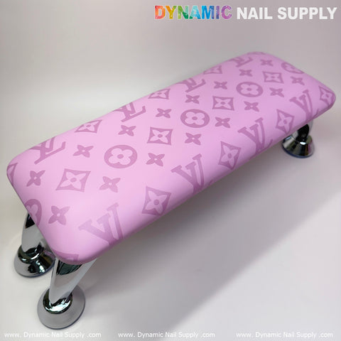 The Big Logo Pink LV Pattern Leather Armrest Cushion Pillow for Pedicure Manicure from Dynamic Nail Supply is perfect for elevating your manicure nails service. With a neutral backdrop showcasing a repeating gradient font of DYNAMIC NAIL SUPPLY along the lower edge, this armrest features chrome legs and a stylish pattern of flowers and letters. Enhance elegance with an optional UV nail light.