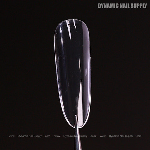 A Natural Round (Long) Full Cover Soft-Gel Nail Tip from the Pink Box held by tweezers on a black background.