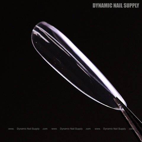 A long, round Natural Full Cover Soft-Gel Nail Tip (Pink Box) held by tweezers; Dynamic Nail Supply text shown.