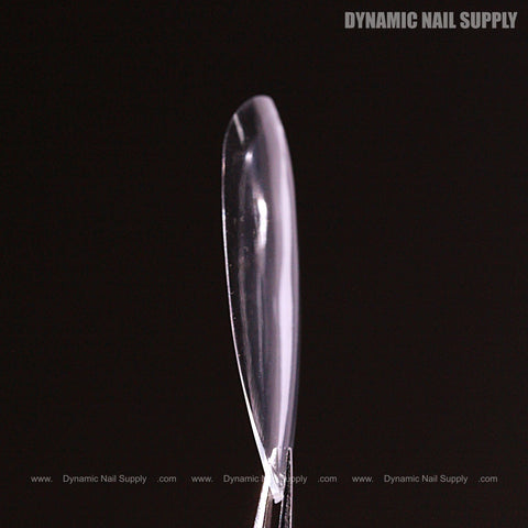 A Natural Round (Long) Full Cover Soft-Gel Nail Tip (Pink Box) held upright by a metal clip on a black background.