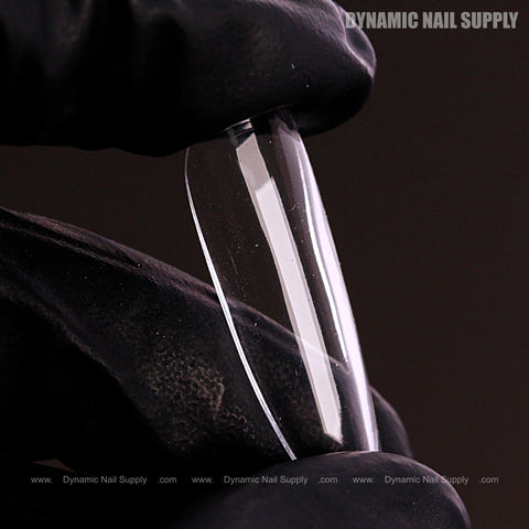 A gloved hand holds a Natural Round (Long) Full Cover Soft-Gel Nail Tip (Pink Box) against a dark background.