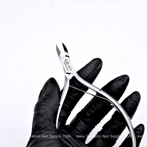 A black gloved hand holds the D01 Jaw 16 stainless steel cuticle nippers—an essential manicure tool.