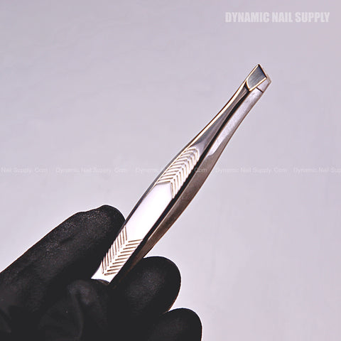 A gloved hand holds the N407 - Professional Tweezers Slanted Head Tweezer Stainless Steel against a light background.