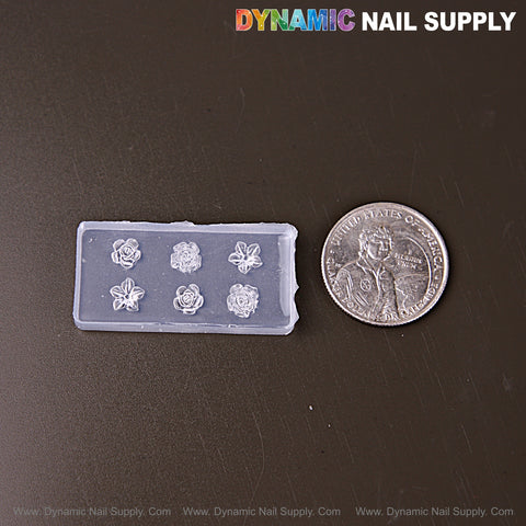 A Tiny Roses and Hibiscus Flowers 3D Nail Art Silicone Mold sits by a U.S. quarter on a dark surface.