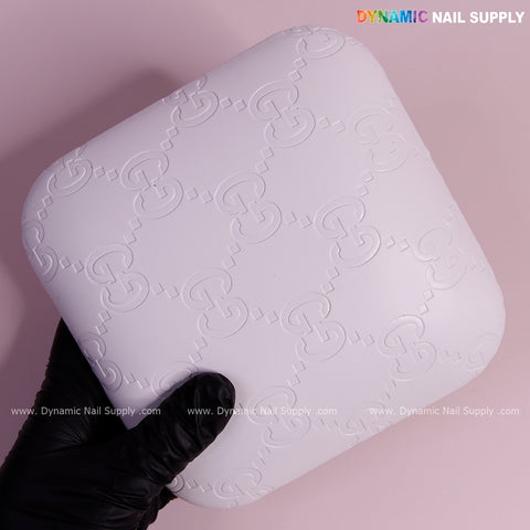 A gloved hand holds the White GC Engrave Elbow Pad Pillow—soft PU leather, supportive, ideal for nail techs.