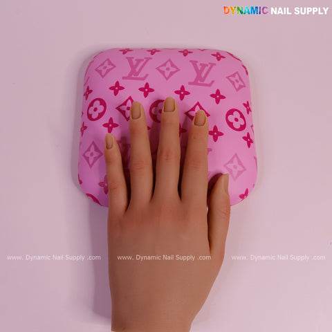 A mannequin hand rests on a Pink and Pink LV Smooth Leather Elbow Cushion Pad Arm Rest Support for nail manicures.