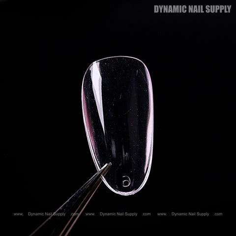 A Natural Almond (Short) Full Cover Soft-Gel Nail Tip held by tweezers, DYNAMIC NAIL SUPPLY in the corner.